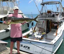 angler holds dorado on the dock close to Yes Aye