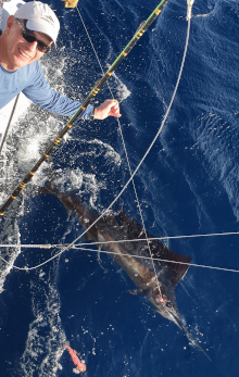 happy client smiles next to his sailfish