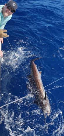 Sandals client smiles next to his sailfish by the boat