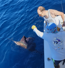 Daniel looks at his sailfish by the boat