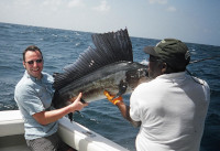 Mr Chalmers with his sailfish in the boat helped by Leslie