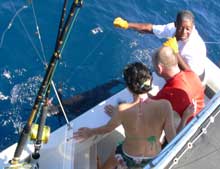 Suzie watches as Leslie holds the sailfish close to the boatsailfish
